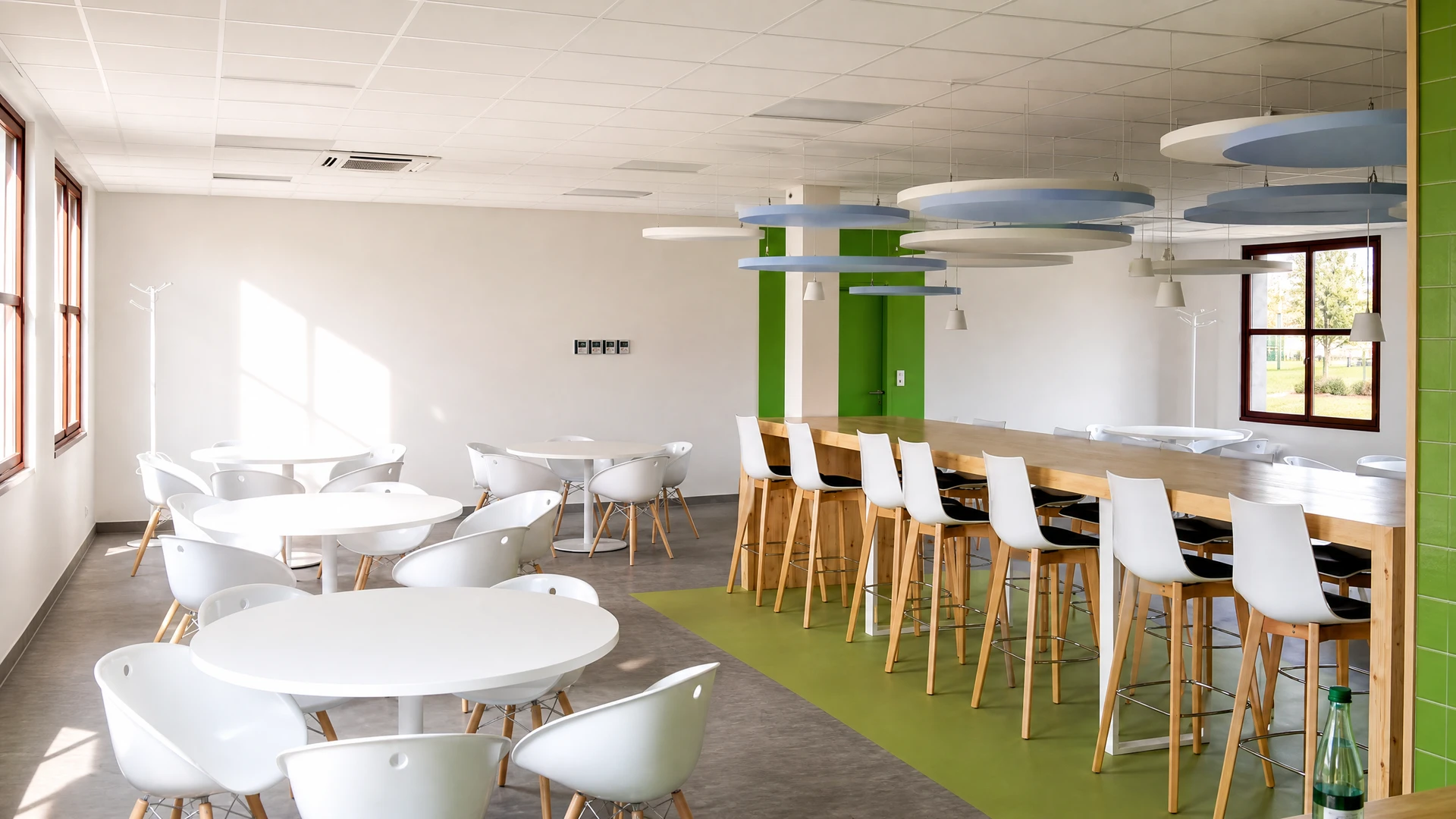 Quatre chaises modernes alignées contre un mur beige, trois blanches et une noire au centre, toutes avec piètement en bois naturel